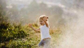 beautiful-little-girl-white-shirt-jeans-runs-lawn-fog-with-great-landscape_8353-7528